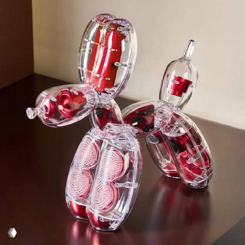 Крупный план прозрачной версии Balloon Dog с видимыми внутренними динамиками и красными компонентами, объект стоит на тёмной поверхности.