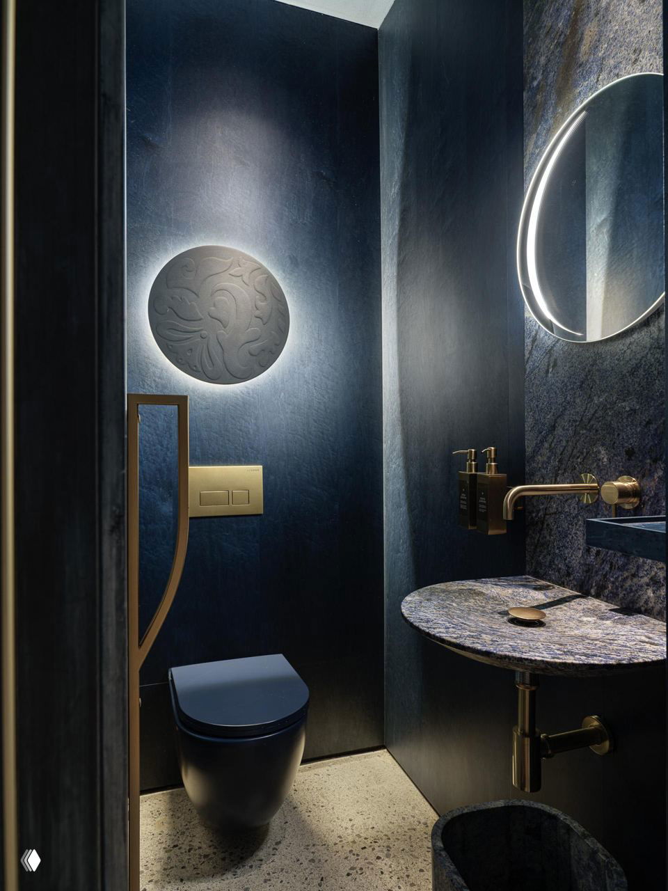 Санузел ресторана: синие стеновые панели, зеркало с подсветкой, керамическая раковина и латунная фурнитура — дизайн выдержан в общей палитре проекта.