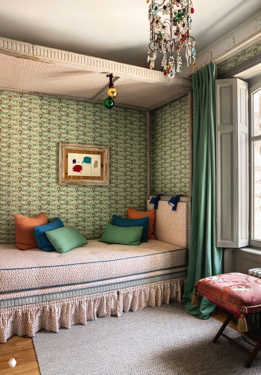 Небольшая обеденная зона или уголок отдыха с тахтой у окна, цветными подушками и тканевыми драпировками — уютный уголок интерьера.