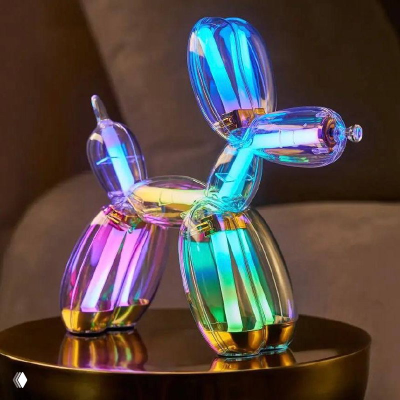Иллюзорно-радужная версия лампы Balloon Dog из хроматической серии: переливы синего, зелёного, пурпурного и жёлтого на тёмном фоне.
