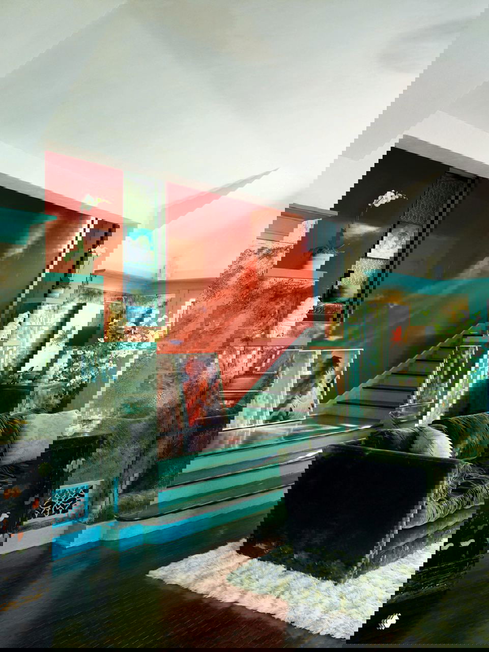 Интерьер с глянцевой красной стеной и зелёными ступенями, зеркалами и декоративными элементами — эклектичный пример смелого дуэта цветов.