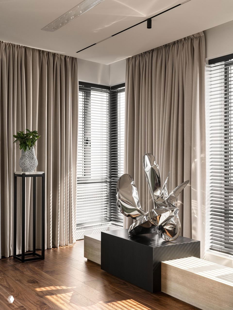 Уютный уголок с большими шторами, декоративной металлической скульптурой и низким подиумом — игра света и текстуры в интерьере квартиры.