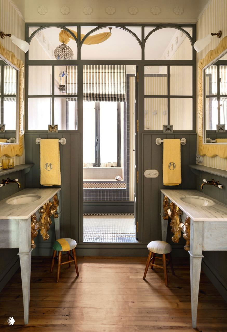 Двойная ванная комната с мраморными раковинами, зеркалами и декоративными полотенцами, стильный ретро-штрих в оформлении пространства.