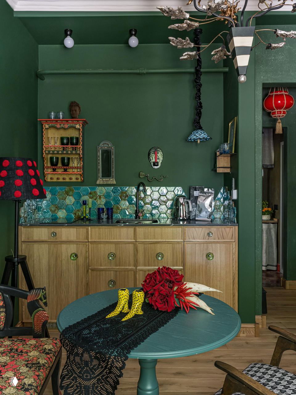 Эклектичный интерьер в темно-зеленых тонах: нижние кухонные модули, цветная мозаика на фартуке и открытые полки, создающие живой визуальный ряд без верхних шкафов.