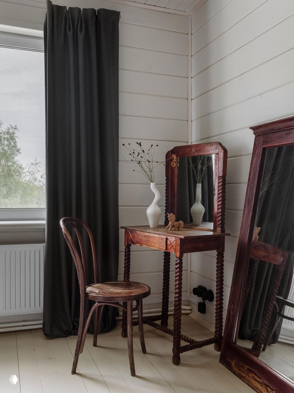 Уютный уголок с деревянным трюмо, стулом и большим напольным зеркалом — винтажный элемент в современном дачном интерьере.