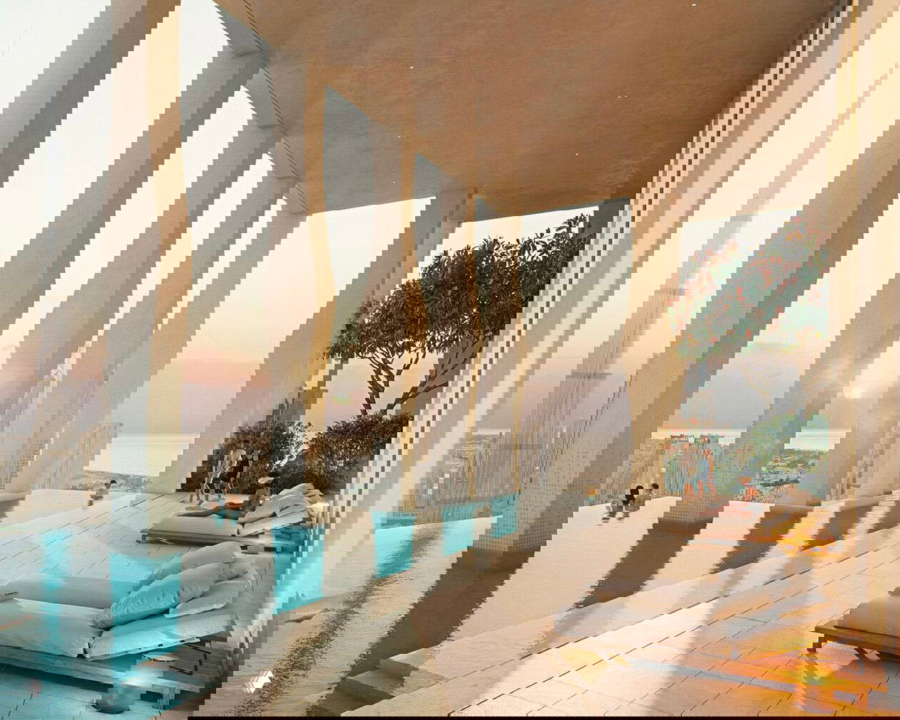 Терасса с инфинити-бассейном в концепции Janu Dubai: колонны, шезлонги и вид на городской горизонт и силуэт Бурдж-Халифы при закате.