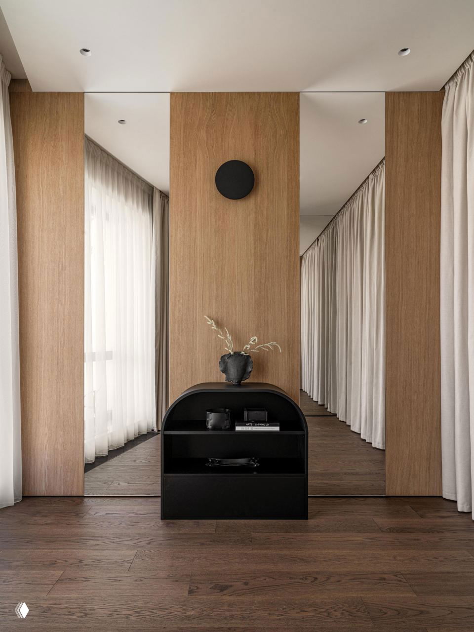 Коридор или зона гардероба с зеркалами, деревянными панелями и небольшим черным комодом — ощущение глубины и спокойного ритма интерьера.