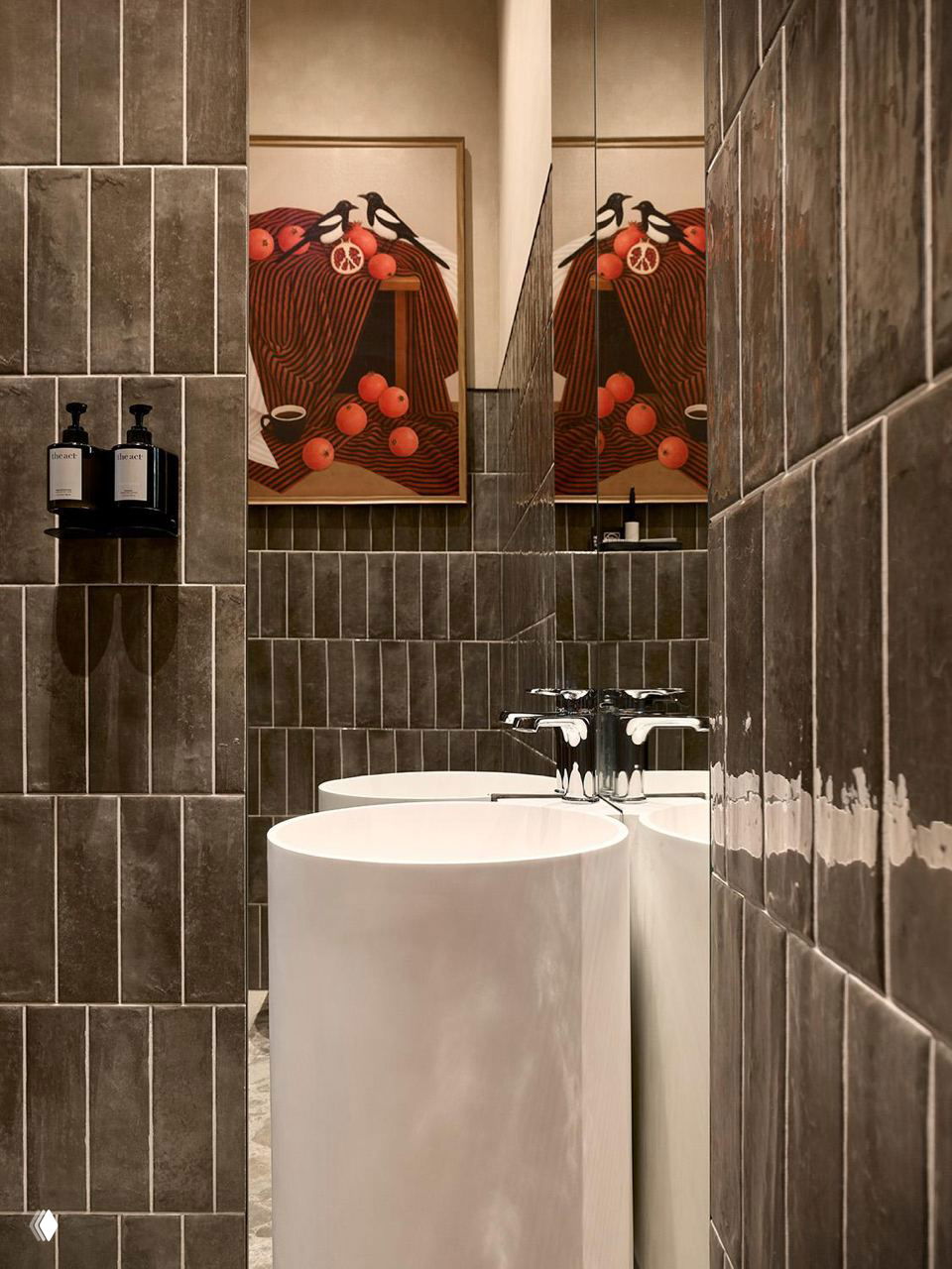 Раковины и плитка в туалетной зоне ANY Coffee Spot: тёмная фактурная плитка, белые колонновидные умывальники и декоративные картины в интерьере.