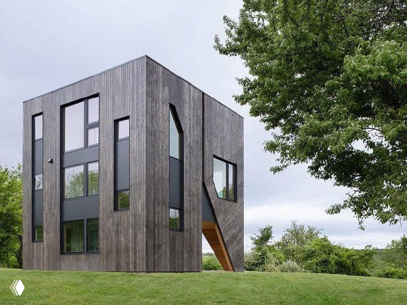 Вид на черный геометричный фасад особняка FORMA рядом с деревом и газоном; фотография содержит визуальные глитчи и искажения.