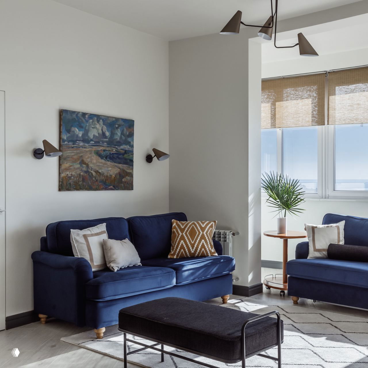 Маленькая гостиная с барной стеллажом и пастельным диваном: настенное бра над диваном и полки с винными ячейками создают атмосферу домашнего бара.