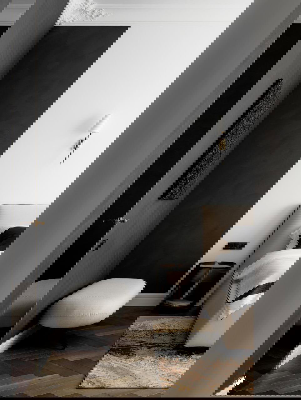 Спальня с контрастной тёмной декоративной стеной и бежевым изголовьем: паркет ёлочкой, мягкая скамья у стены и утончённая лепнина на потолке