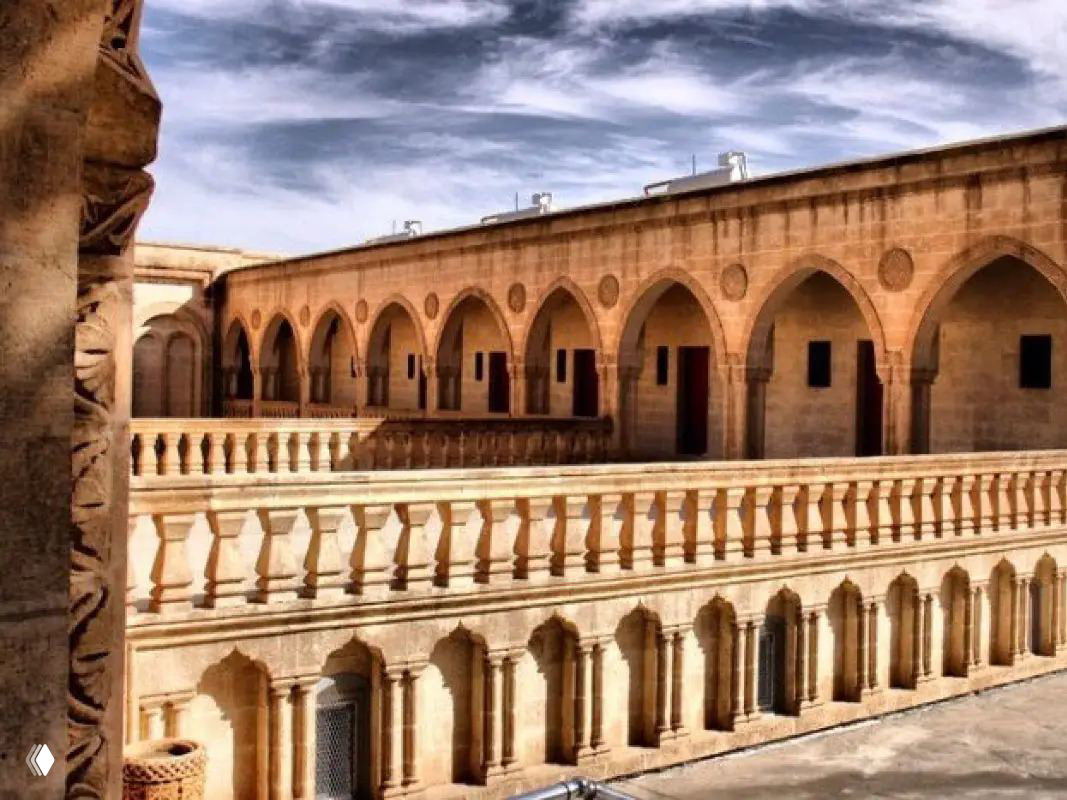 Крытый внутренний двор или галерея из светлого камня в историческом здании Анытлы с арочными проходами и балюстрадами.