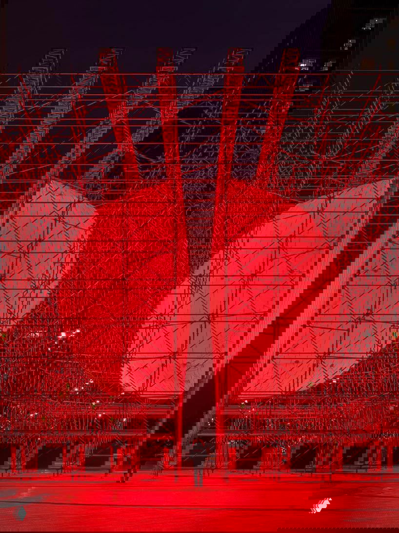 Фронтальный кадр инсталляции DIVIDED: две половины ярко подсвеченной красной сферы внутри металлического каркаса.