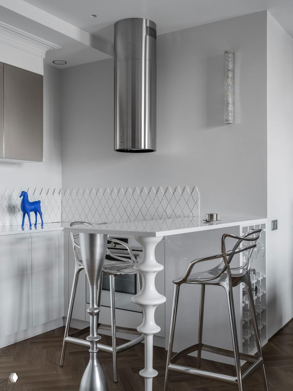 Кухонная зона с белым глянцевым островом и металлическими барными стульями: футуристичные металлические вставки и цилиндрическая вытяжка.