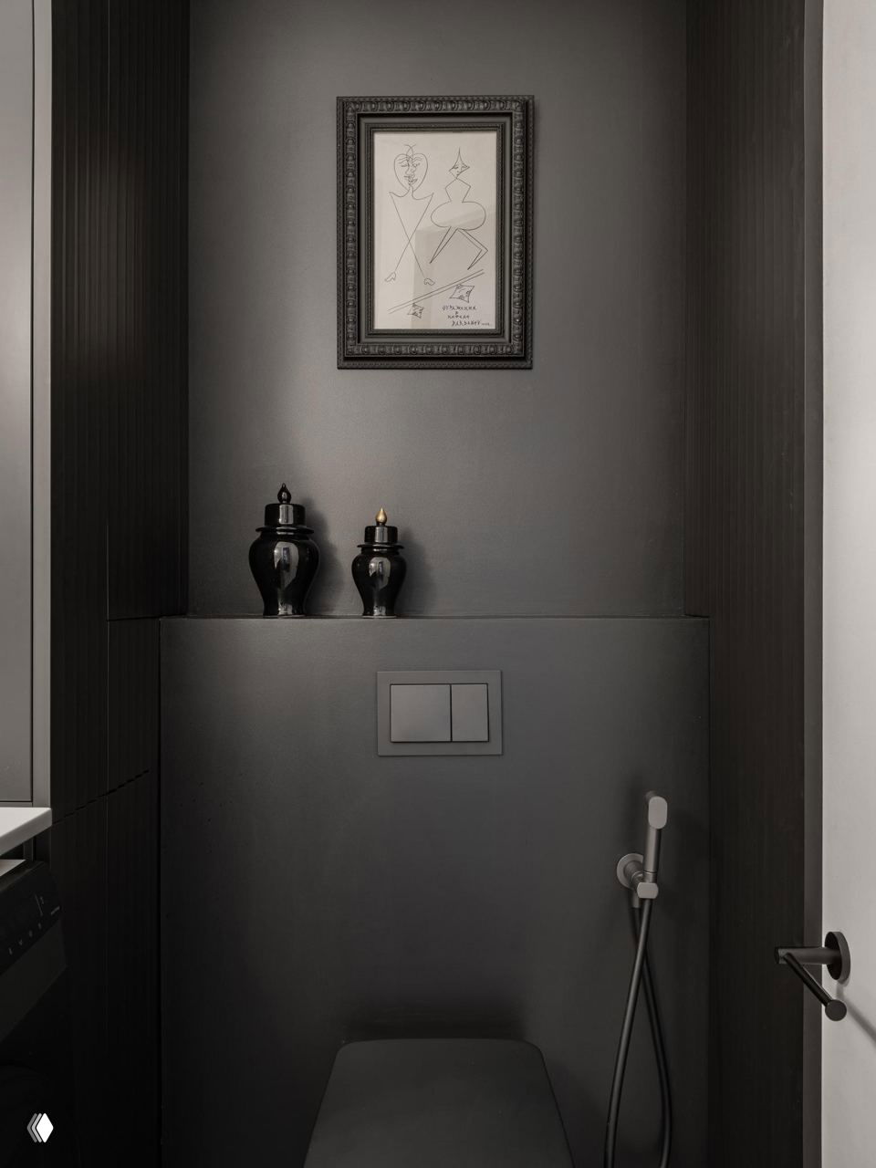 Чёрный санузел с декоративным зеркалом в резной раме, тёмная мебель и стиральная машина встроены под столешницу, плитка с геометрическим рисунком на полу.