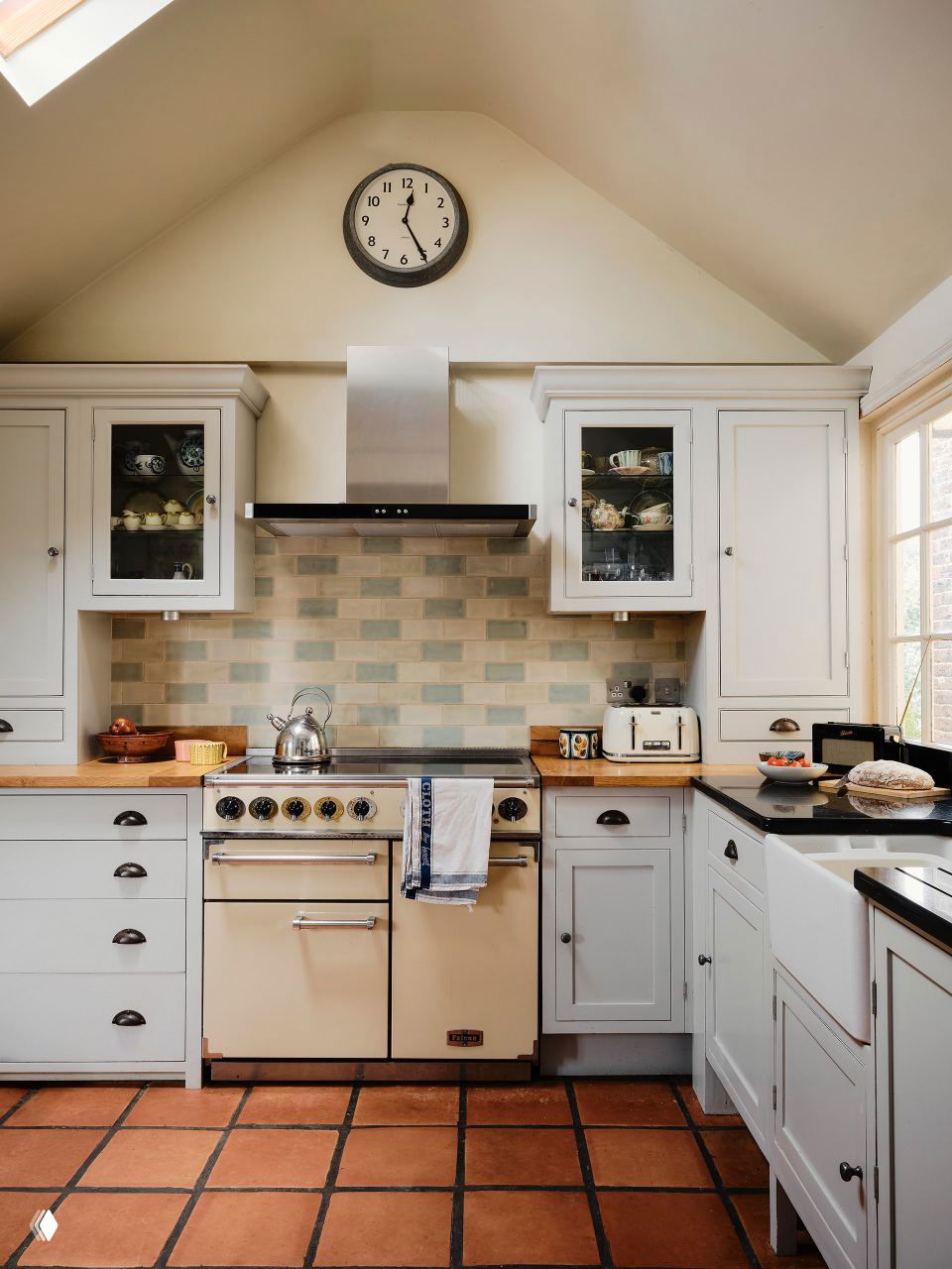 Кухня с кремовой плитой, вытяжкой, открытыми шкафчиками и плиточным фартуком; тёплый пол и деревянные столешницы в традиционном стиле.
