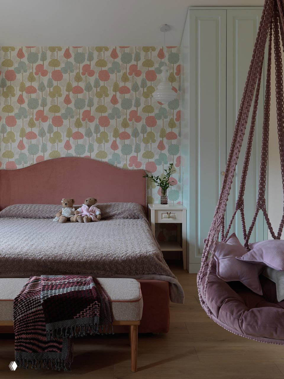 Комната с мягкой розовой кроватью, декоративными обоями и подвесным креслом-коконом — интерьер, сочетающий текстуры и спокойные оттенки для детской