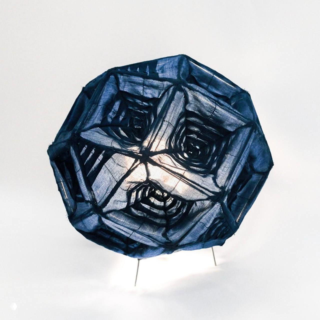 Фронтальный вид лампы Aoi: сферическая конструкция с видимыми квадратными мотивами и проволочными ножками, свет просвечивает ткань.