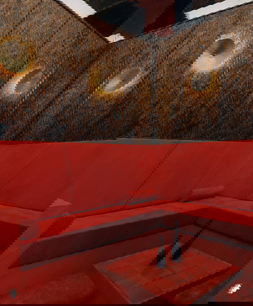 Угловая зона с низким столиком и красным бархатным диваном; тёмные декоративные панели и мягкое освещение задают интимный характер пространства.