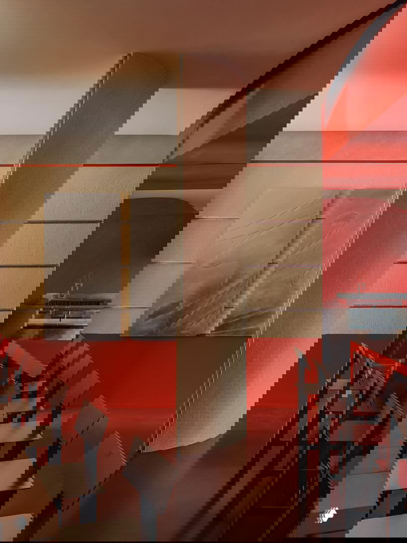 Изогнутый колонный элемент и открытая планировка: сочетание красных стен, металлических панелей и переставляемой мебели формирует текучую схему движения.