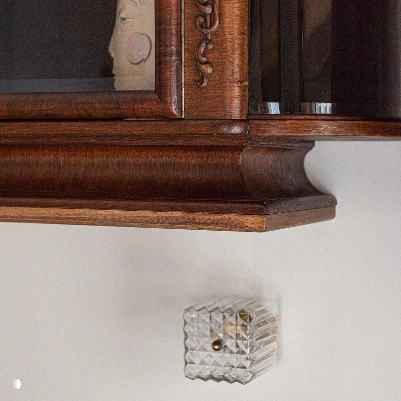 Крупный план деревянного антикварного шкафа и декоративной стеклянной ручки — деталь, показывающая качество обработки и текстуру материала.