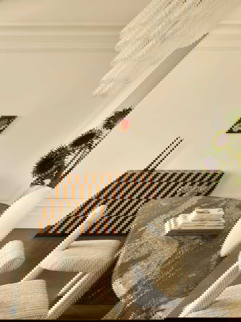 Крупный ракурс столовой и консоли с шахматным орнаментом на фоне светлой стены, мраморный стол и текстурные кресла в нейтральных тонах.