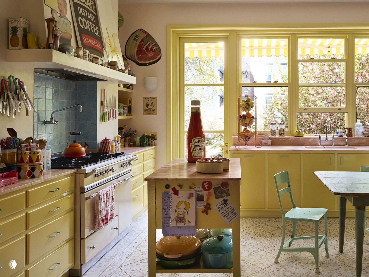 Кухня с желтыми фасадами, деревянным островком и большим окном с видом на сад — домашняя, яркая и эклектичная зона приготовления пищи.