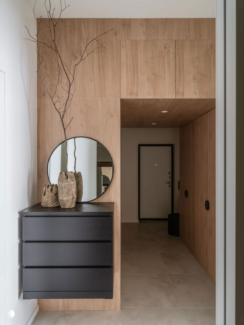 Минималистичная прихожая с крупными плитами нейтрального цвета и панелями из тёплого дерева — пример тренда в пользу натуральных текстур и сдержанных тонов.