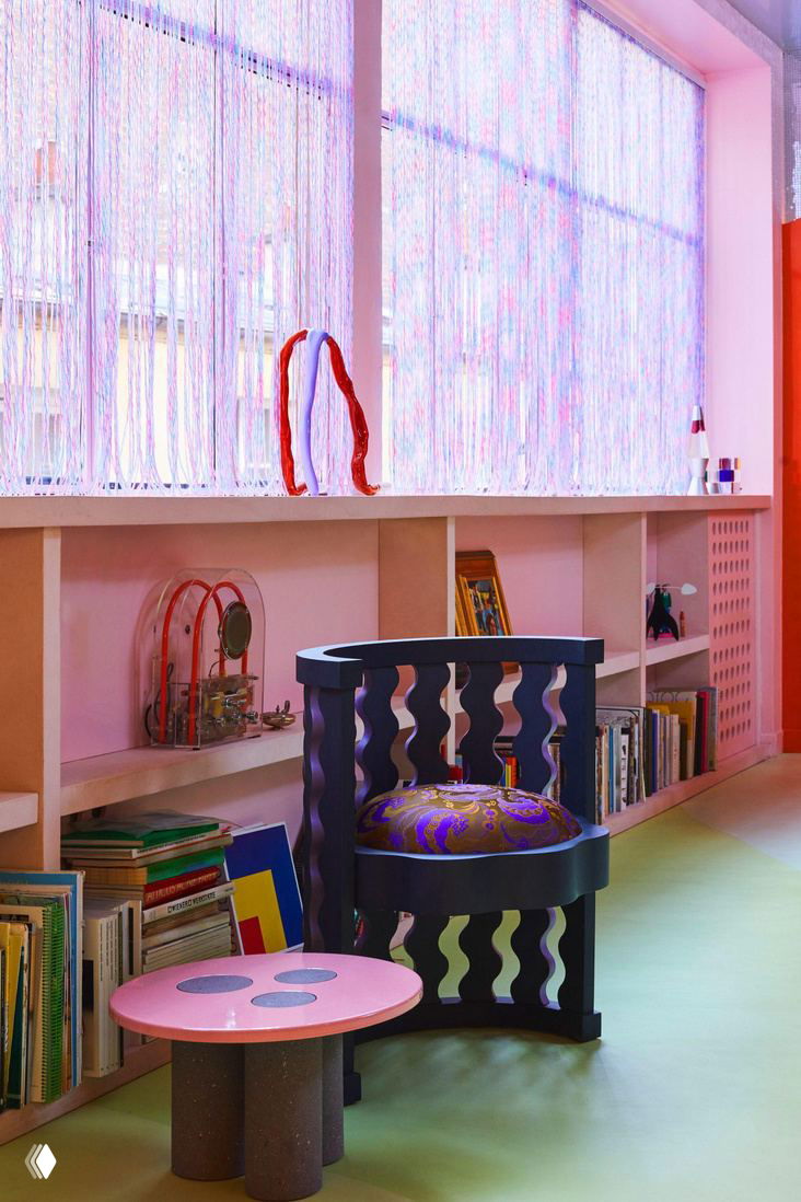 Уютный уголок у окна: темно-синий резной стул, низкий столик и стеллажи с книгами — сочетание пастельных и насыщенных цветов в интерьере.