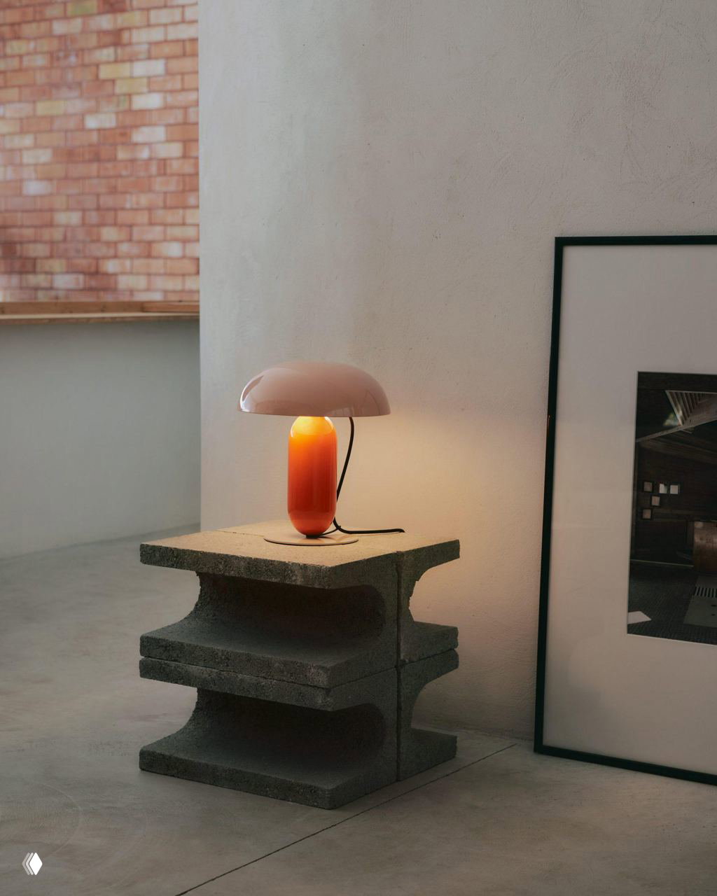 Настольная лампа Gambosa (оранжевая ножка, розовый плафон) на бетонной подставке в минималистском интерьере, тёплый рассеянный свет.
