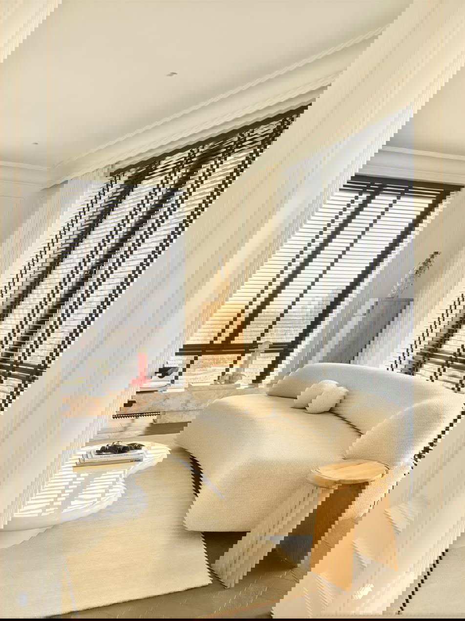 Вид на уютную зону отдыха с мягкими сиденьями, низким белым столиком и текстильными элементами в спокойной кремовой гамме, декоративные подушки-шары.