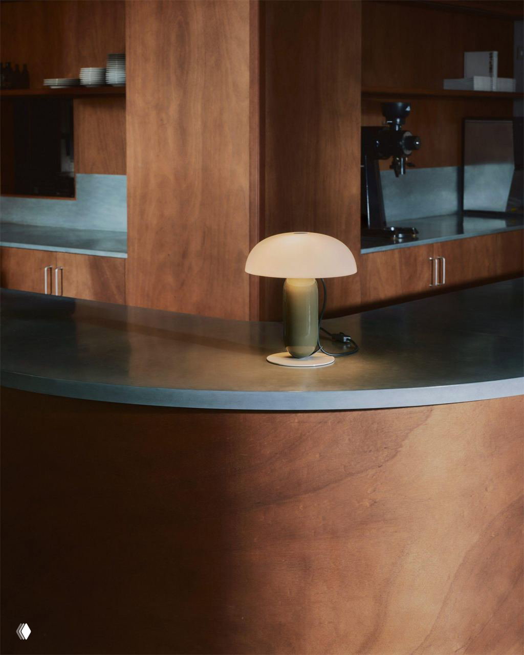 Компактная версия лампы Gambosa в интерьере с деревянной отделкой: зелёная ножка и матовый опаловый плафон создают мягкий локальный свет.
