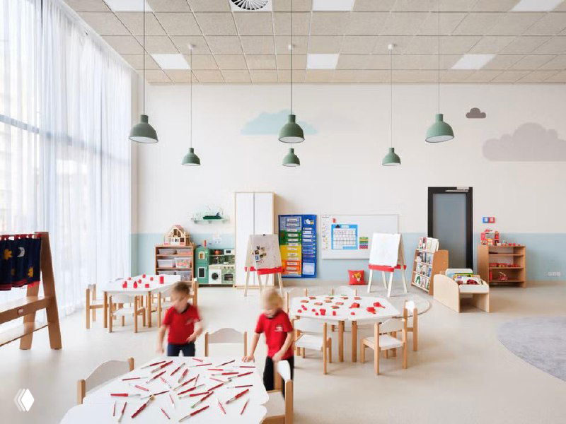 Широкая общая зона с игровыми и образовательными секциями, стеллажами и разноплановыми площадками для активности детей внутри школы SOA.