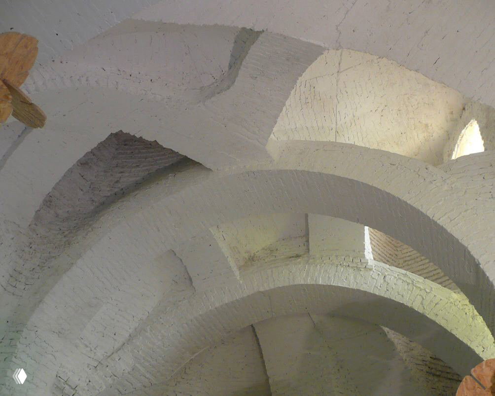 Внутреннее пространство с белыми кирпичными арками и световыми люками; сводчатые потолки и мягкое рассеянное освещение.