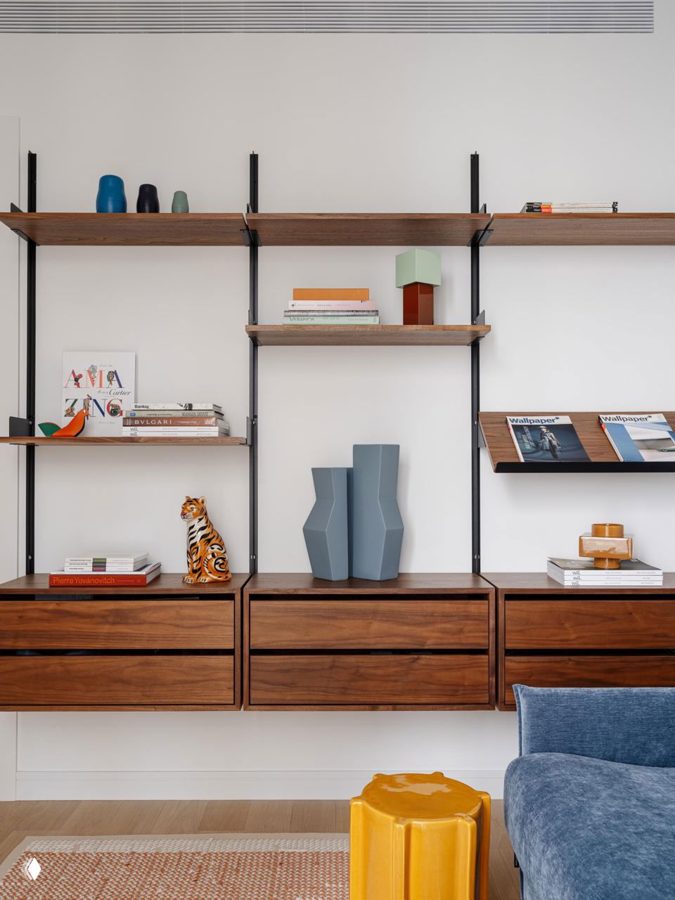 Стеллаж с открытыми деревянными полками и декоративными объектами: книги, вазы и керамика в минималистичном интерьере.