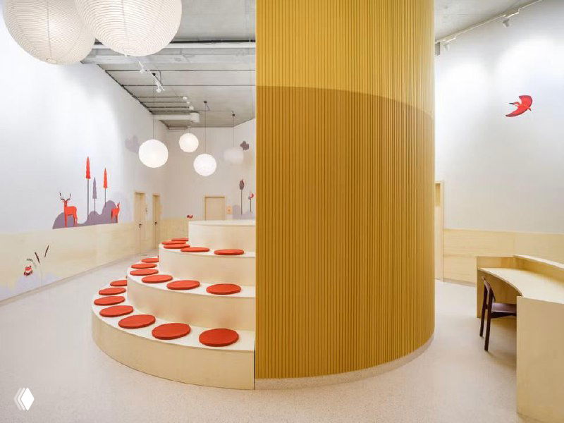 Панорамный вид на центральную часть школы: высокий потолок с подвесными светильниками, мебель для чтения и пространства для групповых занятий.