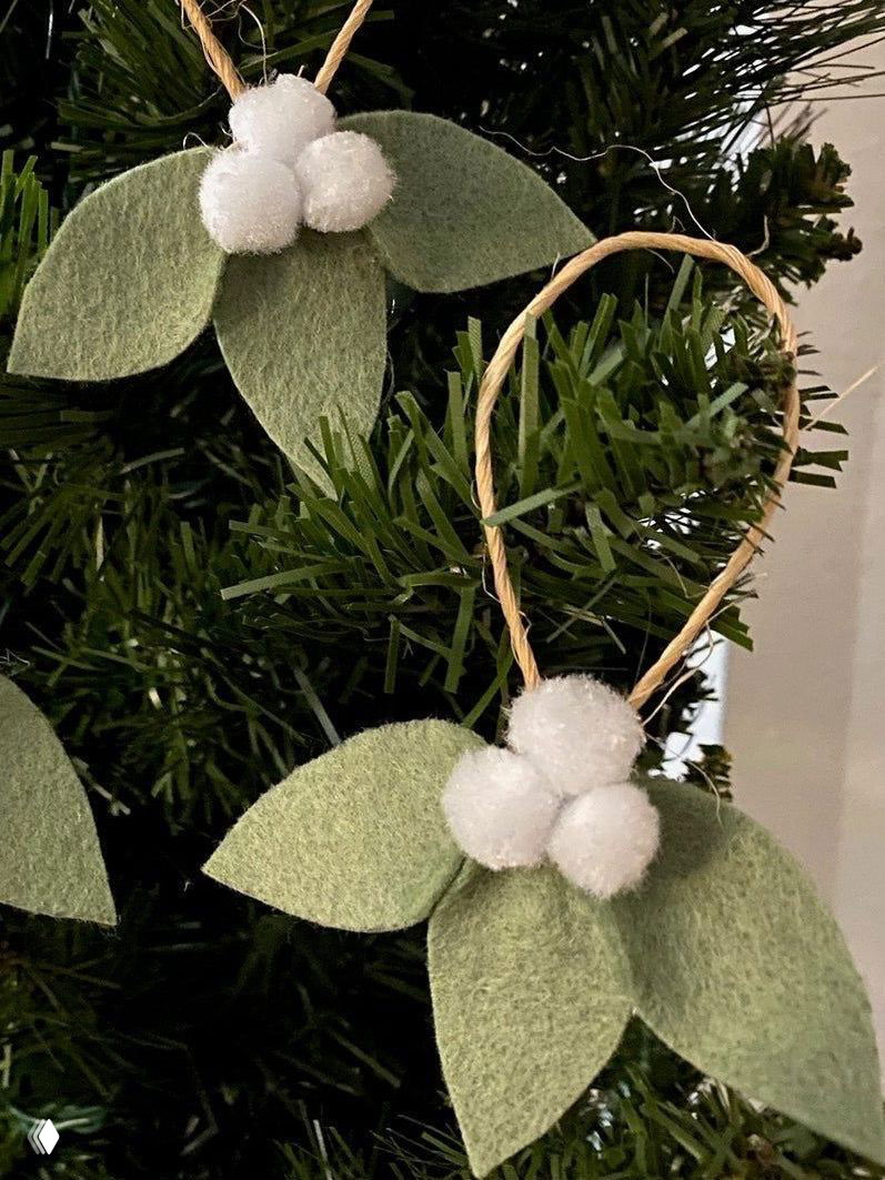 Игрушки-ягоды из фетра и белых помпонов, подвешенные на ёлке; вариант мягких украшений из текстиля и простых декоративных материалов.