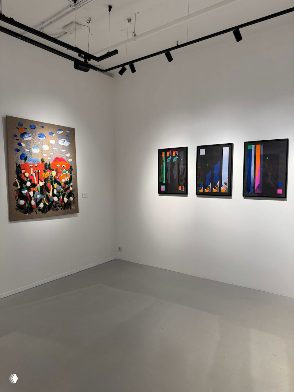 Угол зала с большим живописным полотном слева и тремя современными графическими работами в рамках справа на белой стене.