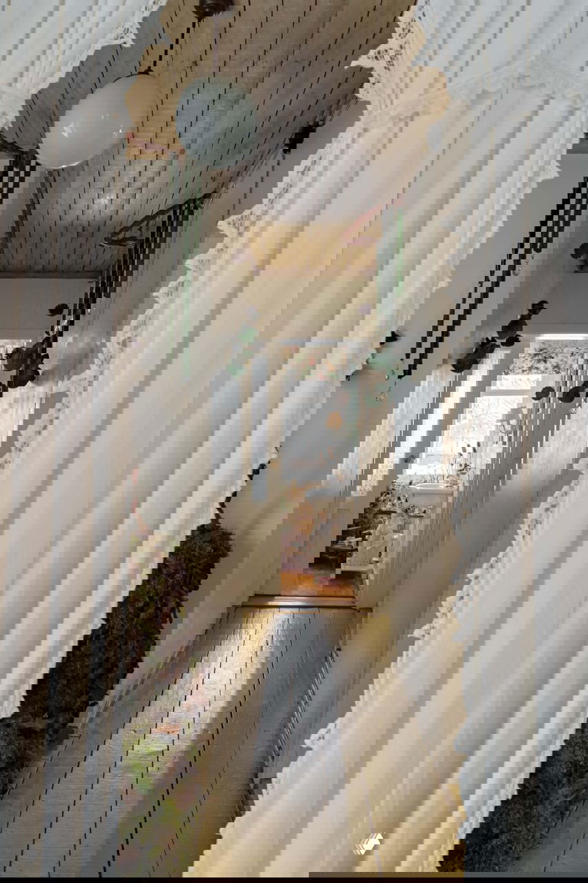 Узкий коридор дачного дома с деревянным полом, воздушными занавесями и подвесными зелёными украшениями — вид внутрь дома и праздничная атмосфера.