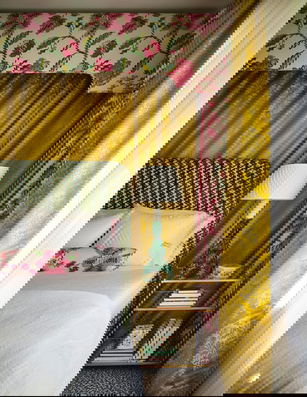 Спальня с узорчатым изголовьем, золотистыми шторами и цветочными текстилями — богатая фактурная композиция для уютной комнаты хозяйки.