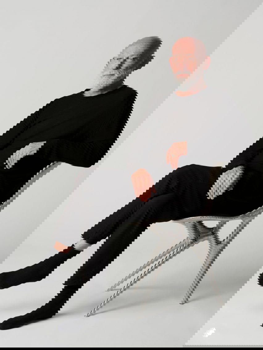 Пожилой мужчина сидит на 3D-печатном металлическом кресле в бионическом стиле в студии; показана финальная посадка и масштаб изделия.