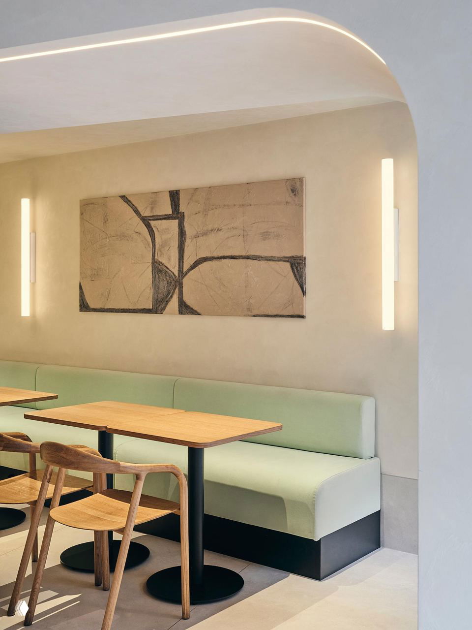 Зона с низкими скамьями и деревянными столами: мягкие мятные диваны, графичное настенное панно и чёрные опоры столов в проекте MODGI Group, баланс теплого и холодного.