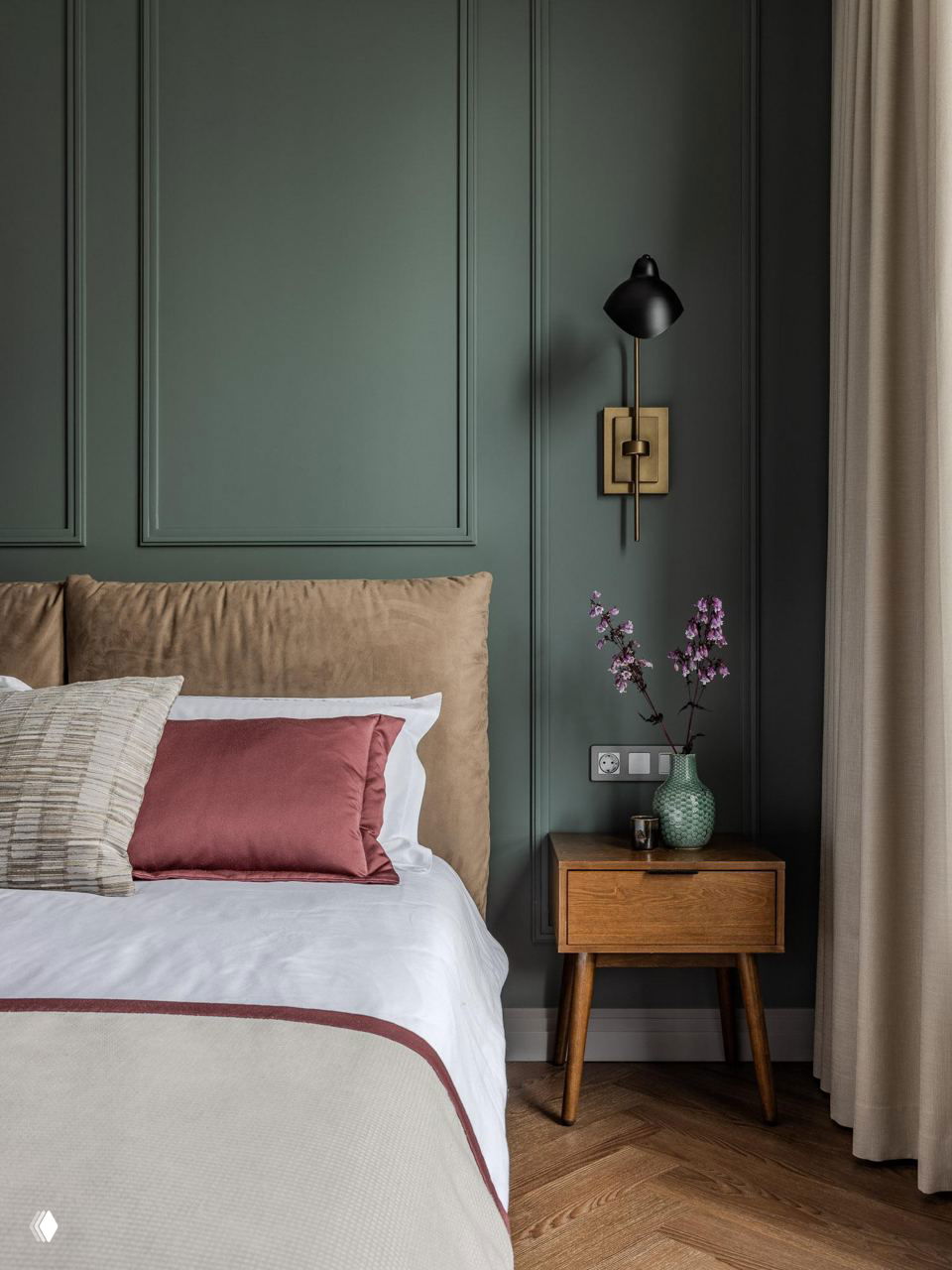 Спальня: бархатное изголовье, глубокое зелёное панно на стене, деревянная прикроватная тумба и стильное настенное бра.