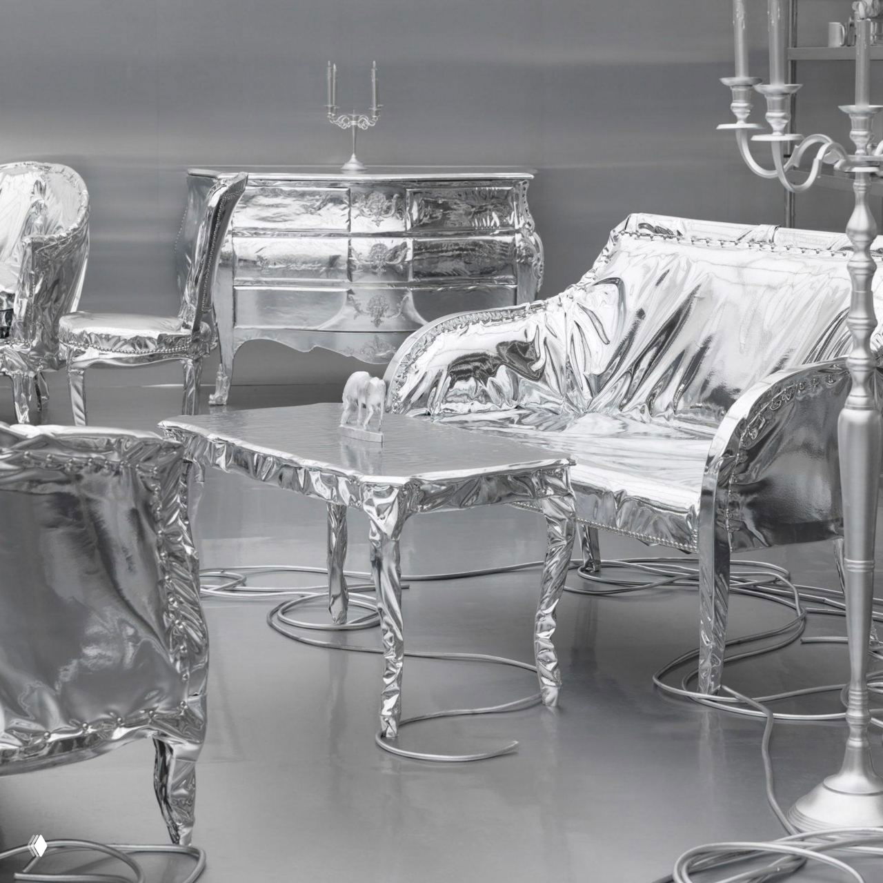 Зона инсталляции с покрытыми серебристой тканью креслами, столами и комодом; драпировки и отражающие поверхности подчёркивают идею присвоения нового смысла вещам.