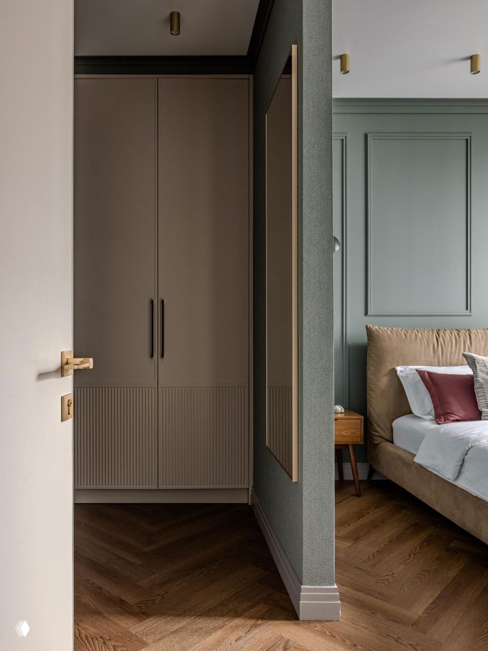 Проход к гардеробной: встроенный шкаф с рифлёными фасадами, нейтральные оттенки стен и тёплый паркет ёлочкой.