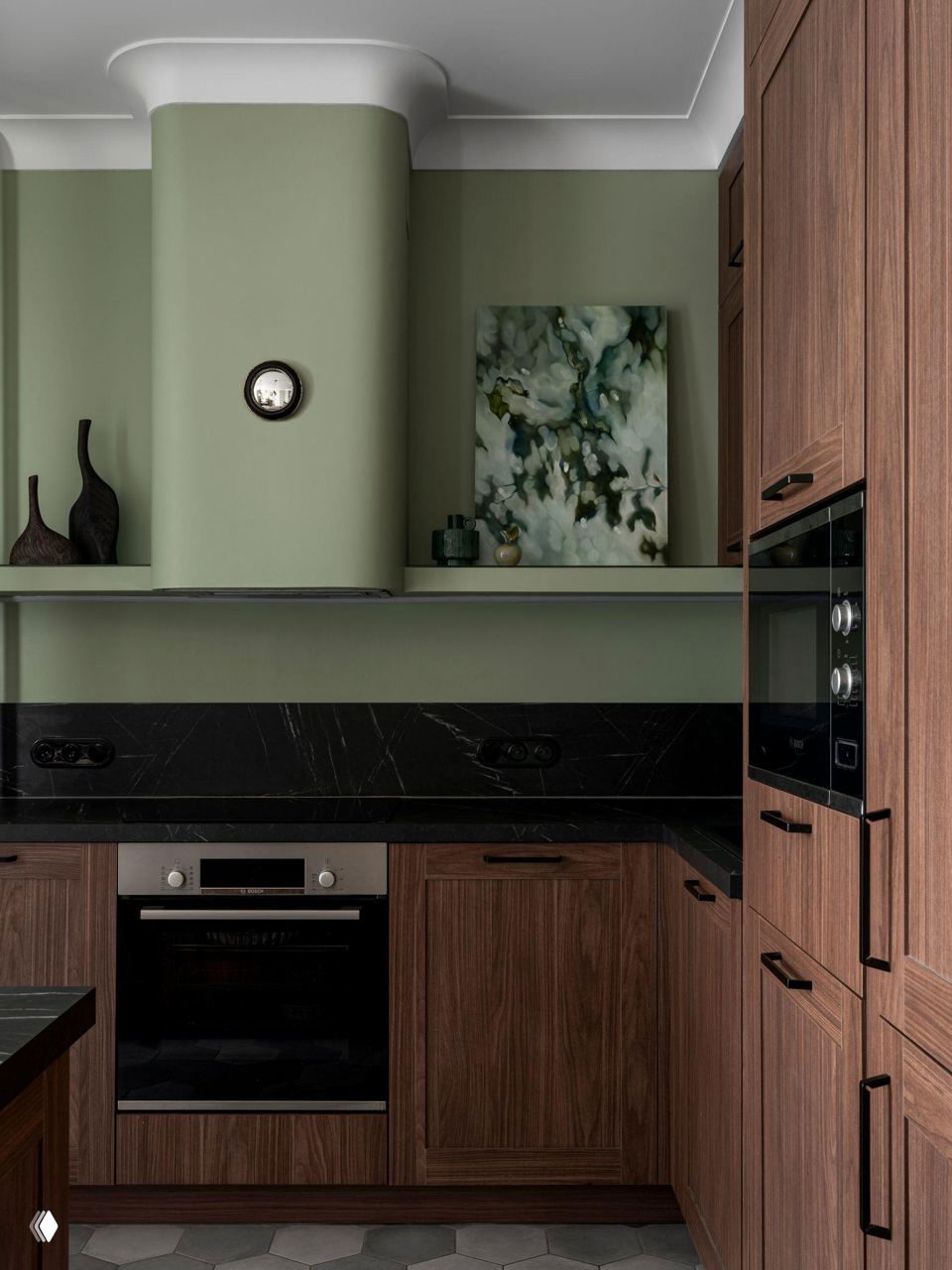 Кухонная зона с деревянными фасадами и чёрной рабочей поверхностью; над плитой декоративный вытяжной короб и картина на полке.