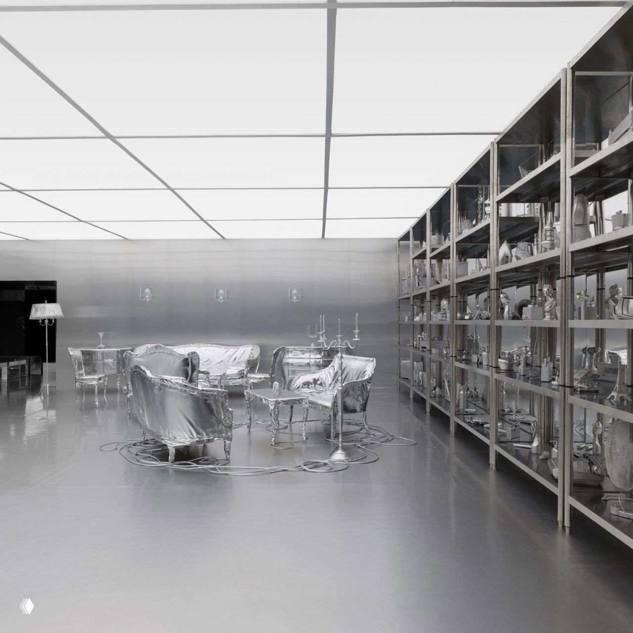 Общий план инсталляции Гарри Нуриева: круговая расстановка покрытой серебристой мебельной группы, отражающие пол и потолок, провода на полу как часть художественной композиции.