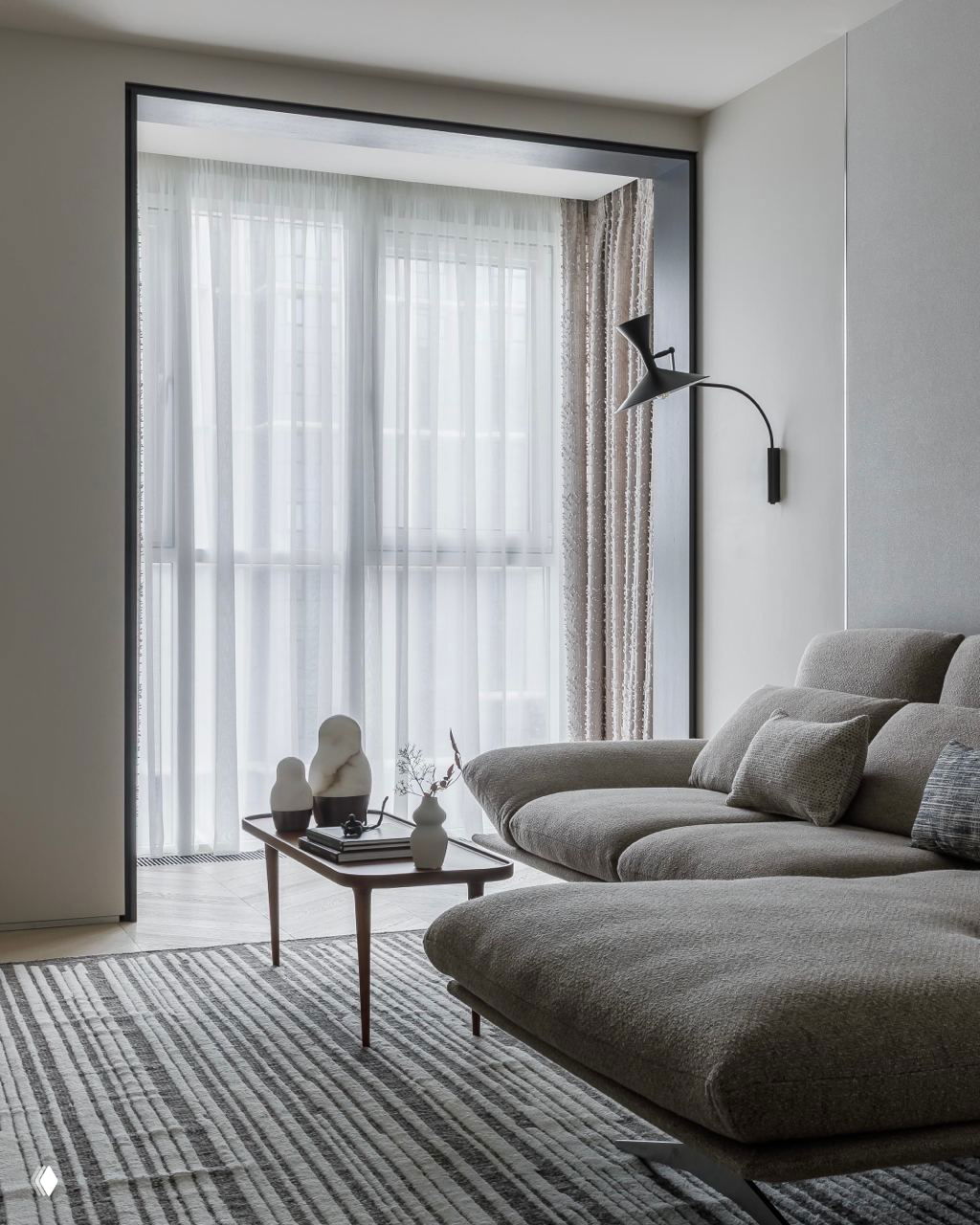 Гостиная с низким модульным диваном и большим оконным проёмом, светлые шторы и лаконичные аксессуары на кофейном столике.