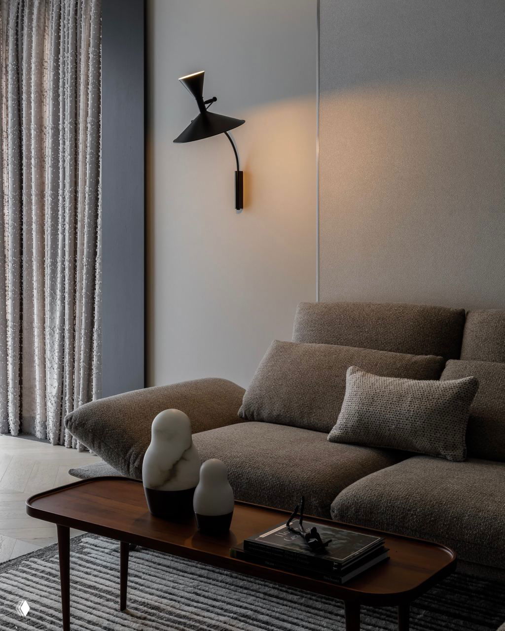 Крупный план дивана с фактурной обивкой, декоративные подушки, настенный светильник и деревянный журнальный столик в спокойных тонах.