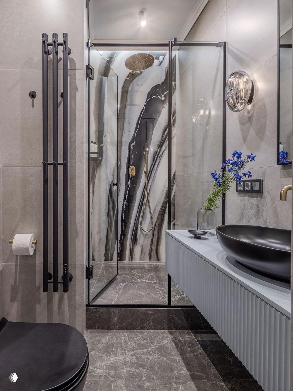 Душевая кабина с прозрачными дверцами, чёрной фурнитурой, золотыми акцентами и эффектной чёрно‑белой мраморной стеной за душем.